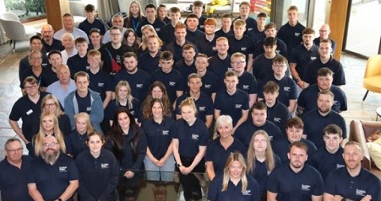 Group of people in matching Scottish Water branded polo shirts posing for a photo indoors