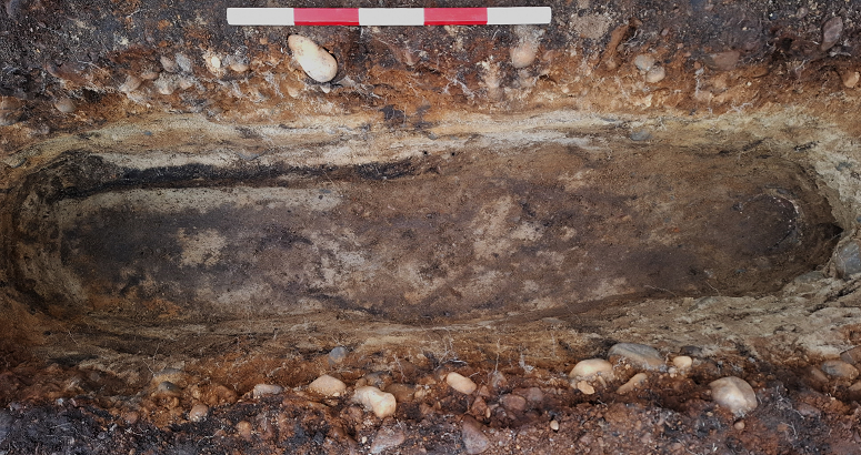 Final excavation image of grave showing surviving cranial elements to right and stain of bod