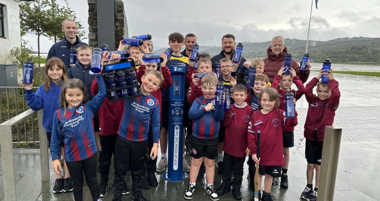Group of adults and children posing behind brand new water refill station